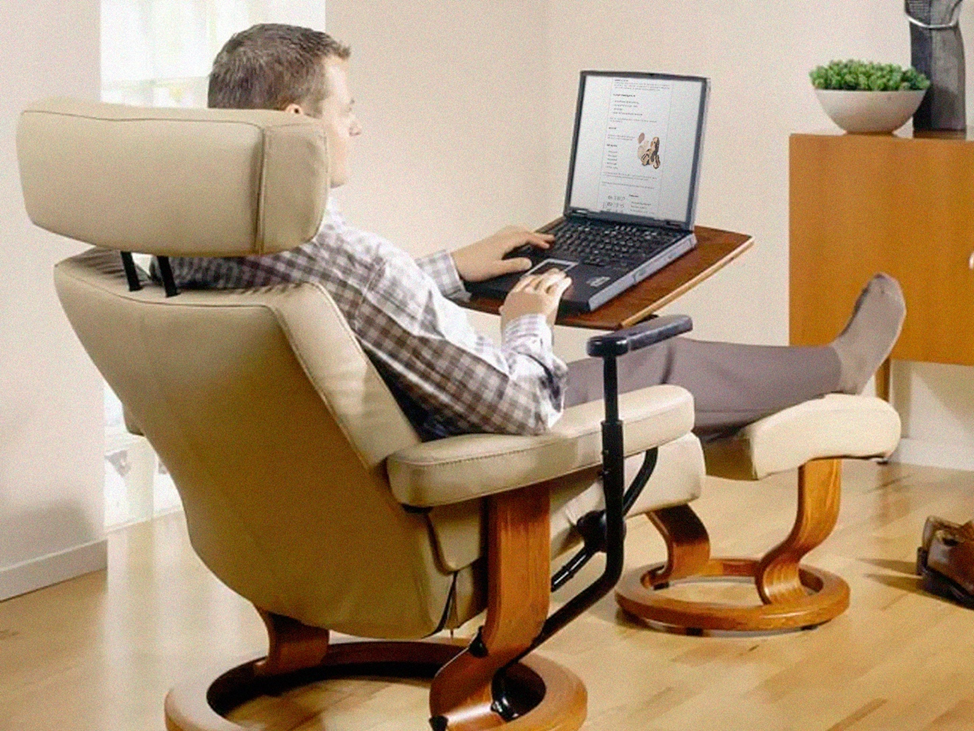 Мужчина сидит в мягком кресле с ноутбуком